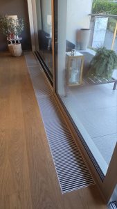 Close-up of Fidoks FOKS BREEZE floor convectors installed in the luxury flat house.